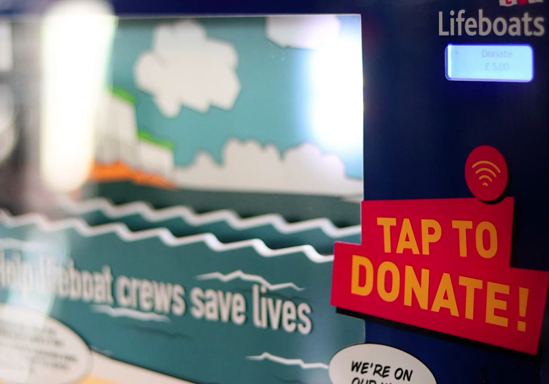 Photo of a bespoke donation box created for the RNLI charity, showing a contactless payment reader alongside an animatronic lifeboat display.